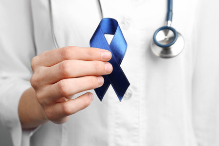 Doctor holding blue awareness ribbon, closeup view. Symbol of medical issuesの写真素材