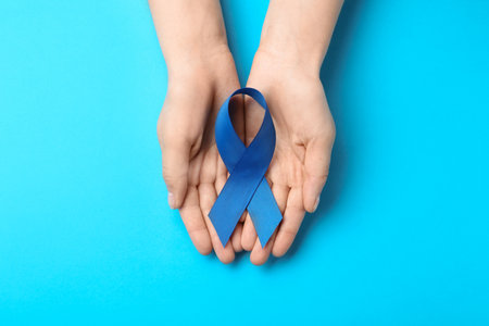 Woman holding blue awareness ribbon on color background, top view. Symbol of social and medical issuesの写真素材