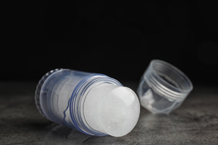 Natural crystal alum deodorant and cap on gray table against black backgroundの写真素材