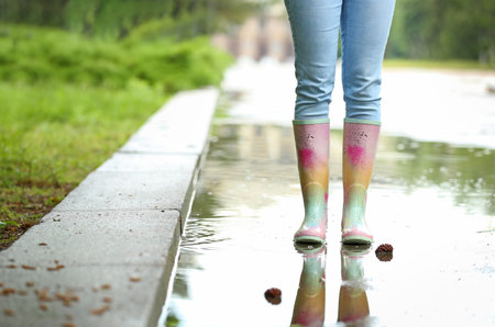 Woman with rubber boots in puddle, closeup. rainy weatherの写真素材