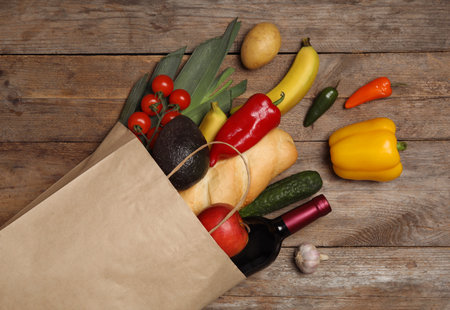 Shopping paper bag with different groceries on wooden background, flat layの写真素材