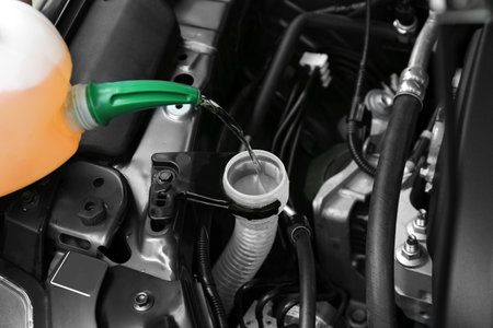 Pouring liquid from plastic canister into car washer fluid reservoir, closeupの写真素材