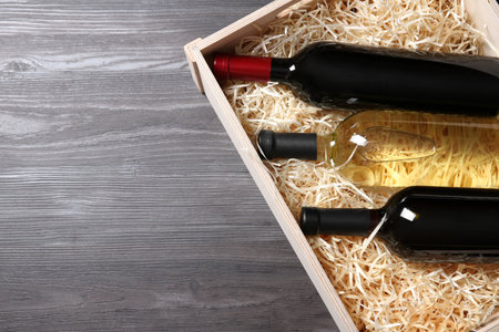 Wooden crate with bottles of wine on gray table, top view. Space for textの写真素材