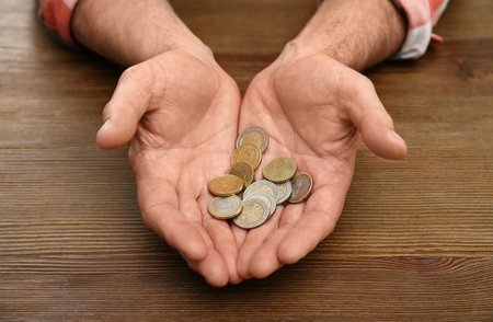 Senior man holding coins in hands at table, closeup