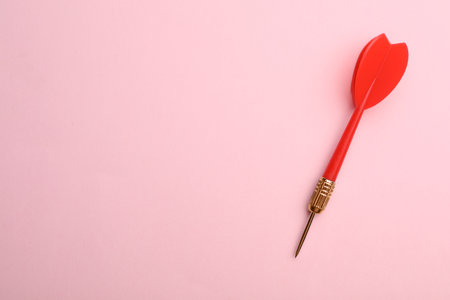 Red dart arrow on pink background, top view with space for textの写真素材