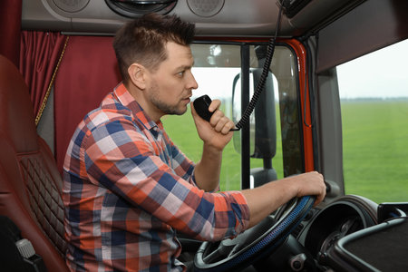 Driver using CB radio in cab of modern truckの写真素材
