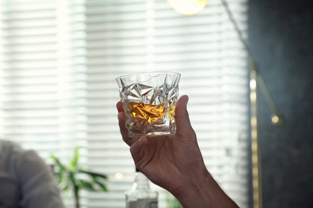 Man with glass of whiskey indoors, closeup viewの写真素材
