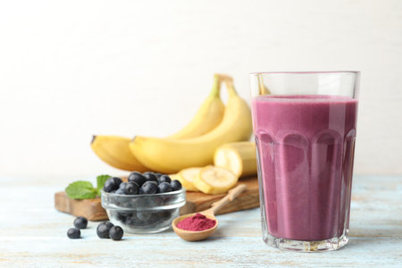 Fresh acai drink with berries and bananas on wooden table against light backgroundの写真素材