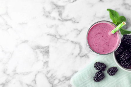 Delicious blackberry smoothie in glass on marble table, top view. Space for textの写真素材