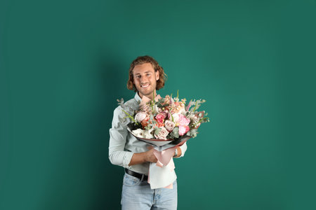 Young handsome man with beautiful flower bouquet on green backgroundの写真素材