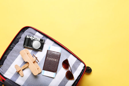 Open suitcase with beach objects on yellow background, top view. Space for textの写真素材