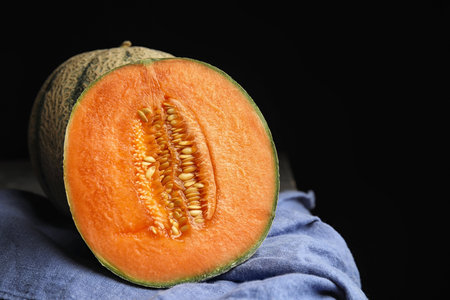 Tasty ripe cantaloupe melons on napkin against black backgroundの写真素材
