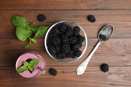 Flat lay composition with fresh blackberries and smoothie on wooden table