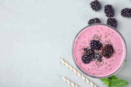Flat lay composition with glass of delicious blackberry smoothie on light table. Space for textの写真素材