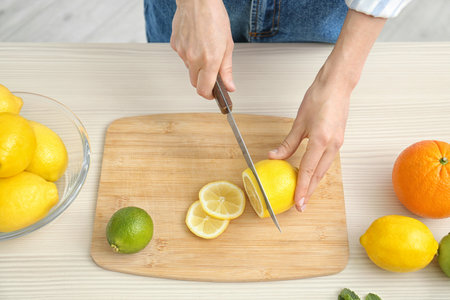 Woman cutting fruit for making natural detox lemonade at table, closeupの写真素材