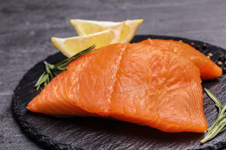 Slate plate with salmon fillet on gray table, closeupの写真素材
