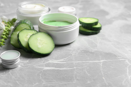 Jars of body cream and cucumber slices on gray marble background. Space for textの写真素材