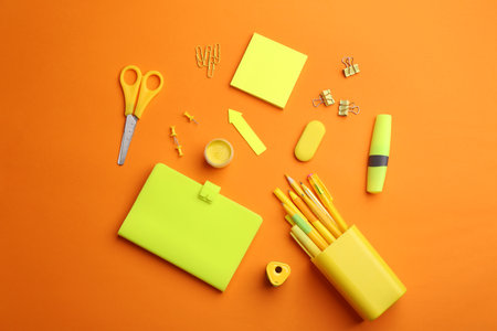 Different bright school stationery on orange background, flat layの写真素材
