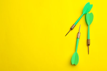 Green dart arrows on yellow background, flat lay with space for textの写真素材