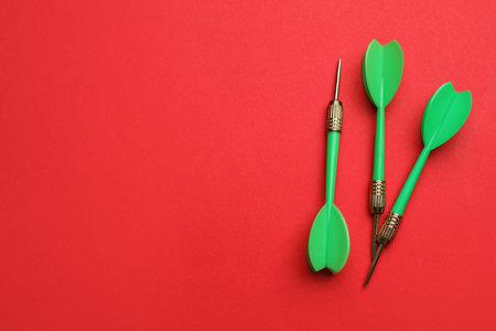 Green dart arrows on red background, flat lay with space for textの写真素材
