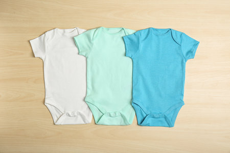 Different baby bodysuits on wooden background, top viewの写真素材