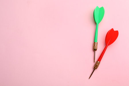 Plastic dart arrows on pink background, flat lay with space for text