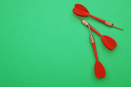 Red dart arrows on green background, flat lay with space for text
