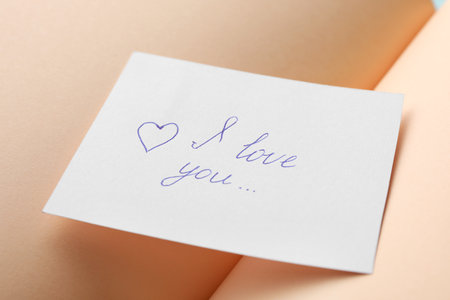 Paper sheet with words I LOVE YOU on open notebook, closeupの写真素材