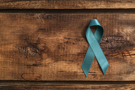 Teal awareness ribbon on wooden background, top view with space for text. Symbol of social and medical issuesの写真素材