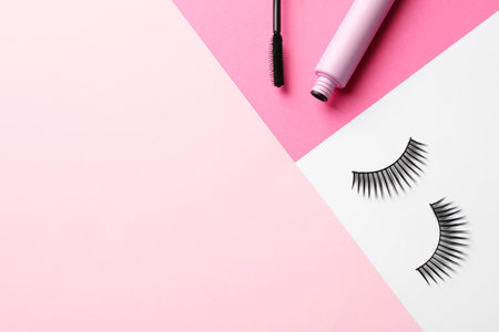 False eyelashes and mascara on color background, flat lay. Space for textの写真素材