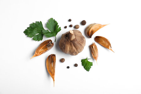 Aged black garlic with parsley and peppercorns on white background, view from aboveの写真素材