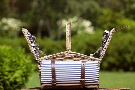 Picnic basket with blanket on wooden table in gardenの写真素材