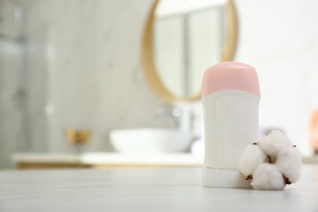 Deodorant with cotton flower on table in bathroom. Space for textの写真素材