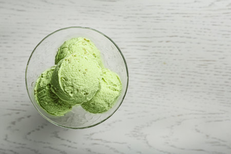 Delicious green ice cream served in dessert bowl on white wooden table, top view. Space for textの写真素材