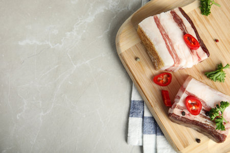 Board with bacon and pepper on gray stone background, flat lay. Space for text