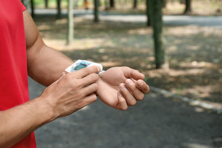 Young man checking pulse with medical device after training, closeup