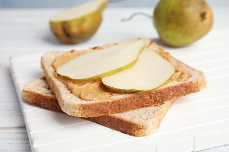 Slice of bread with peanut butter and pear on white boardの写真素材