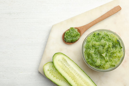 Handmade face mask made and fresh cucumber on white wooden table, flat lay. Space for textの写真素材