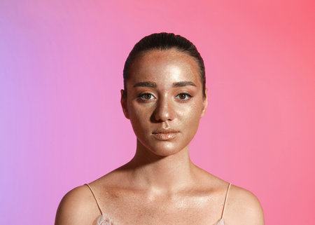 Beautiful young woman with glitter makeup on colorful backgroundの写真素材
