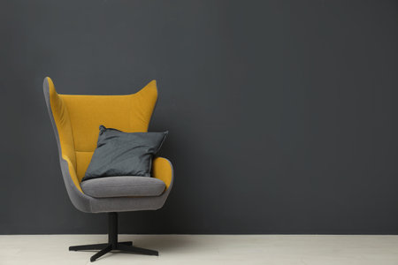 Stylish room interior with comfortable armchair and floor lamp near black wall. Space for text