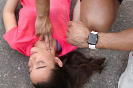Young man checking pulse of unconscious woman on street