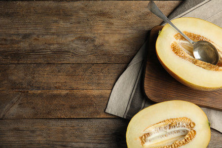 Cut ripe melon and spoon on wooden table, flat lay. Space for textの写真素材