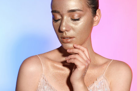 Beautiful young woman with glitter makeup on colorful background