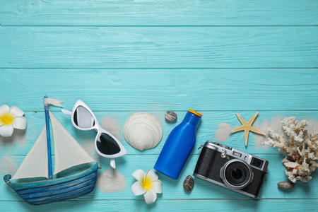 Flat lay composition with stylish beach accessories on light blue wooden background, space for text