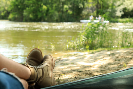 Young man resting in camping tent on riverbank, view from inside