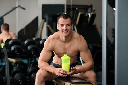 Athletic young man with protein shake in gymの写真素材