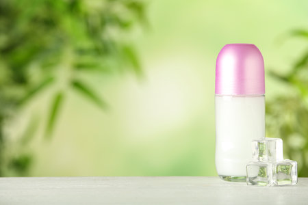 Deodorant container and ice cubes on white wooden table against blurred background. Space for text