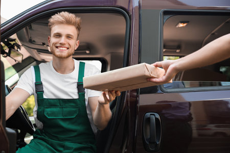 Young delivery courier giving parcel to customer outdoors