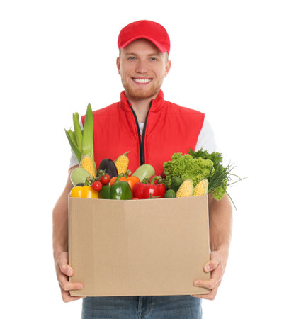 Delivery man with box of fresh vegetables on white backgroundの写真素材