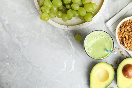 Flat lay composition with tasty avocado smoothie on gray marble table. Space for text